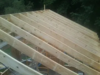 New roof rafters set over an addition before sheathing in Ava