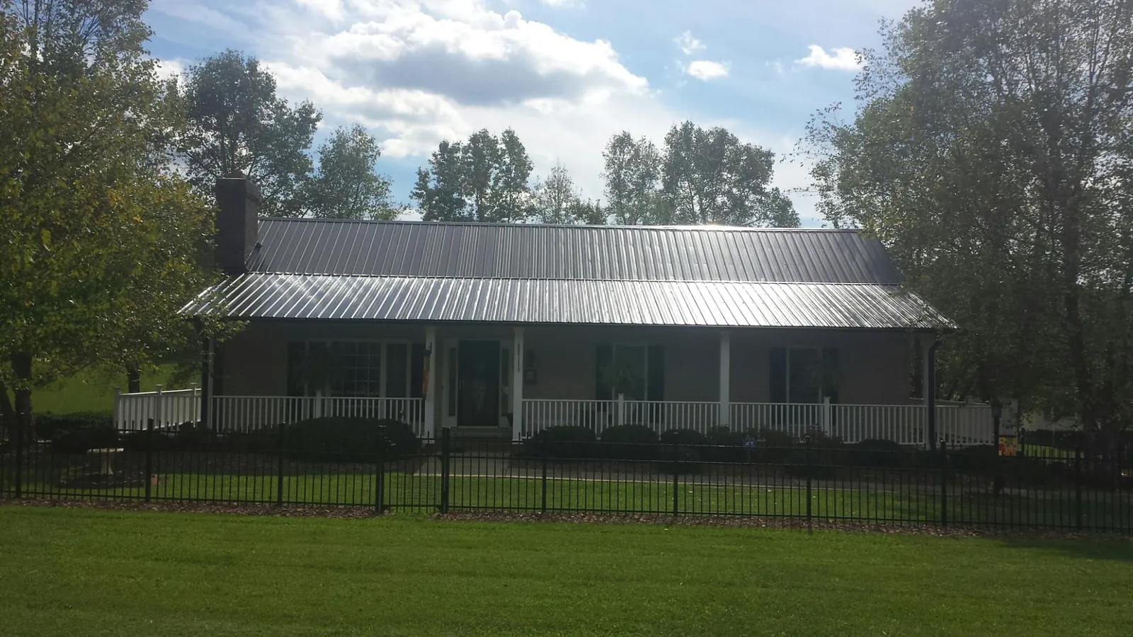 Gray metal roof on a brick ranch with a full width front porch — Gutter Guard Installation work by our crew in Ava