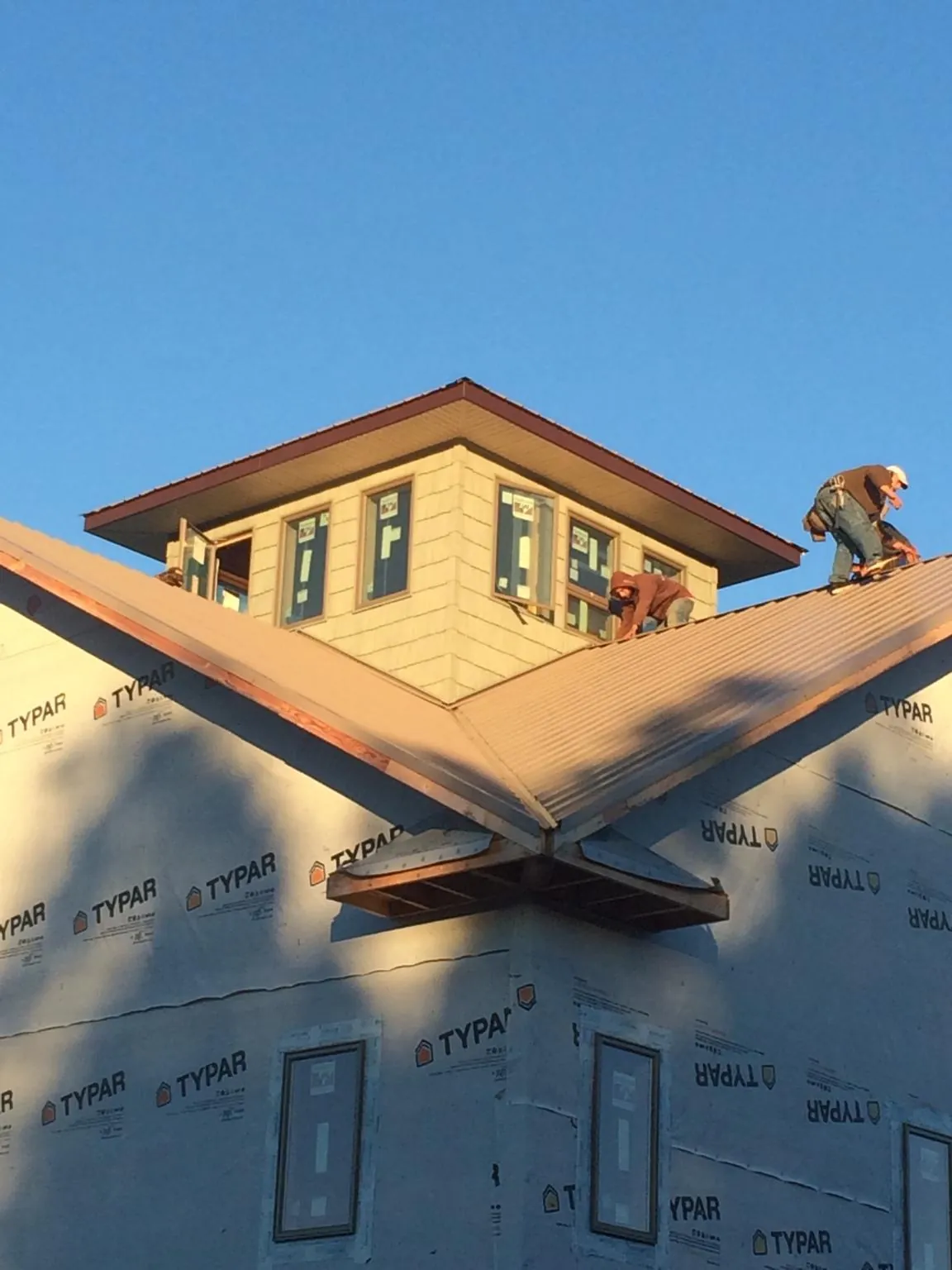 Roofers working around a rooftop cupola on a new metal roof at sunset — Roof Waterproofing in Ava by Roofing Brothers